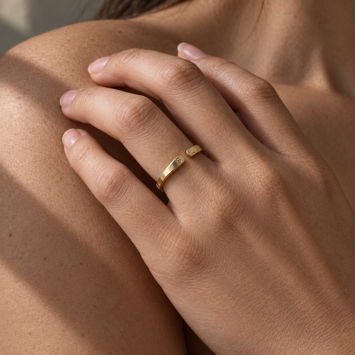 Anello dorato indossato, mano sulla spalla e ombra morbida