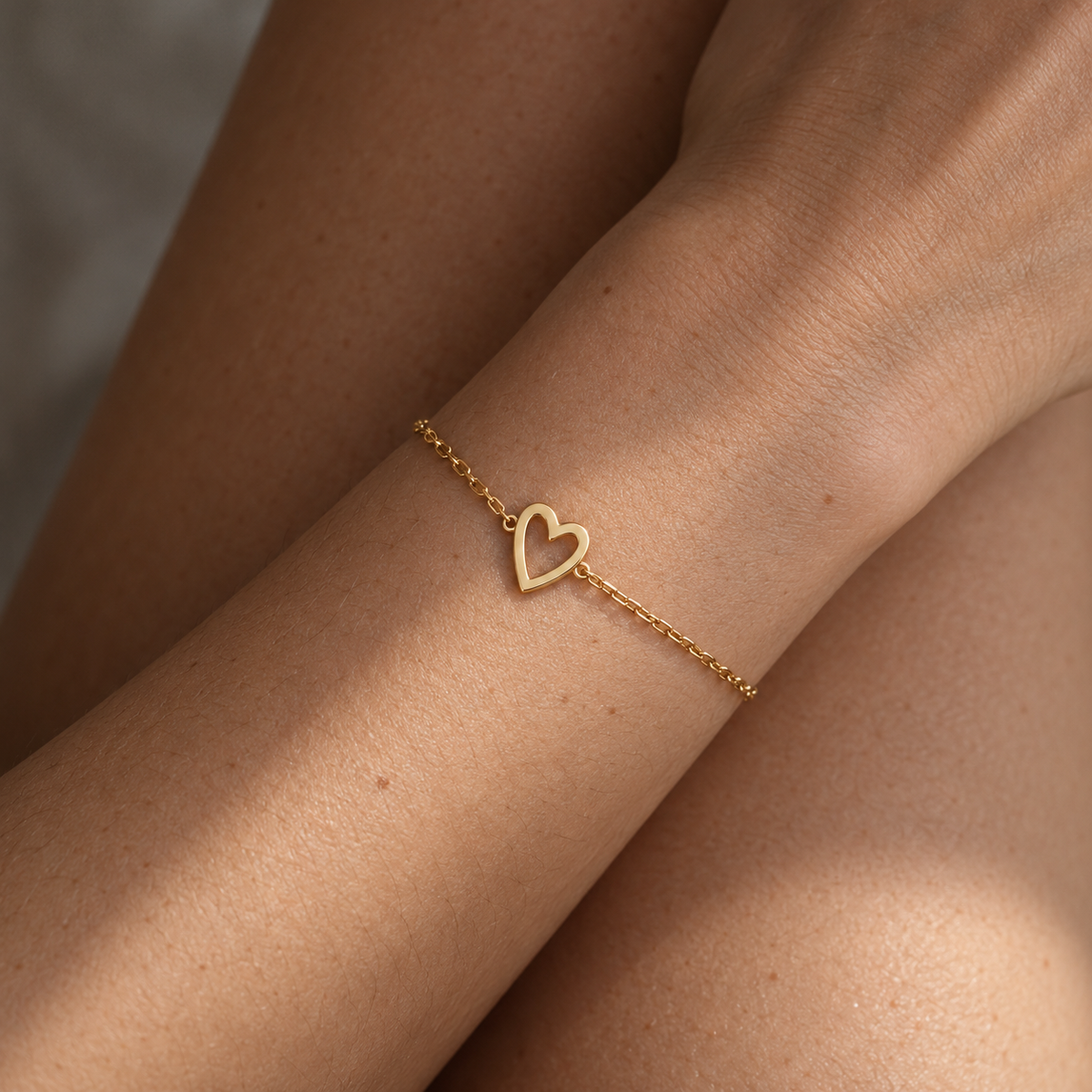 Bracciale cuore dorato su un solo polso, dettaglio sulla pelle