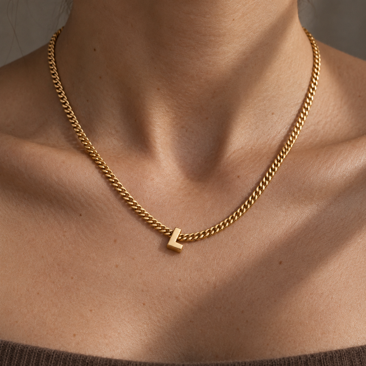 Collana con iniziale L sulla pelle, luce morbida e ombre delicate