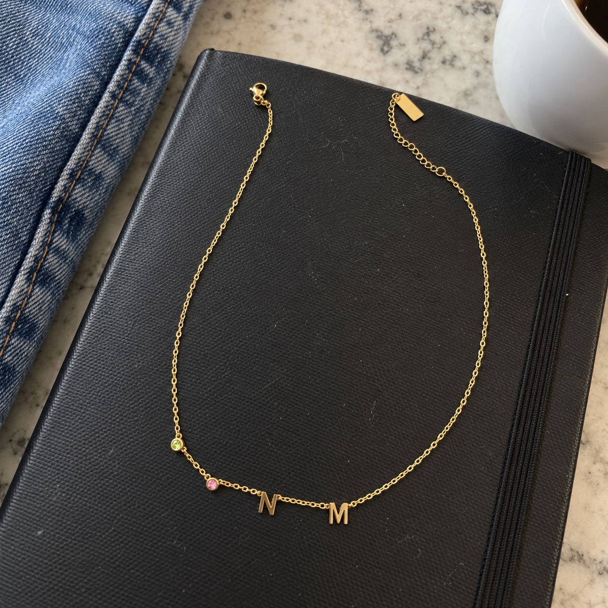 Collana dorata con pietre verde e rosa e iniziali N e M